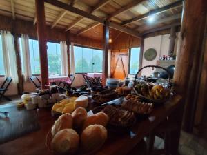a table with a bunch of bread and other foods on it at Chalés românticos com hidromassagem e lareira em área rural de visconde de Mauá Pousada Bela Helena in Visconde De Maua