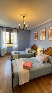 a bedroom with two beds and a chandelier at Casa Pilar Casa Llara, En el paraíso, cerca de todo in Ujo