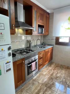 a kitchen with wooden cabinets and a stove top oven at Casa Pilar Casa Llara, En el paraíso, cerca de todo in Ujo