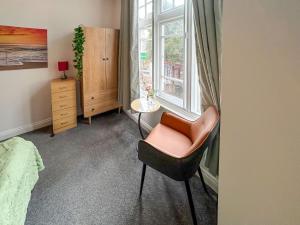 a bedroom with a chair and a window at Flat One in Weymouth +2 photos