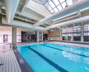 a large swimming pool with blue water in a building at Modern 2BR Luxury Apartment - Amazing Location, Steps To Everything! in Vancouver