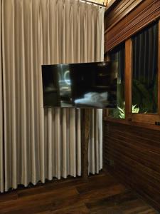 a flat screen tv sitting on a stand next to a window at Uma Cabins by Uma Experience in Penginyahan