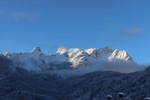 a mountain covered in snow with clouds in front of it at Al Roser in Forno di Zoldo