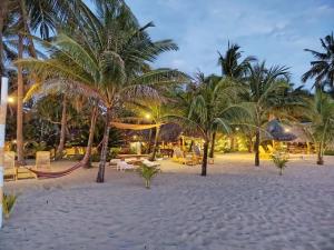 a resort with palm trees on the beach at night at Bermuda Beach Resort in Lagob