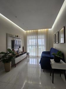 a large living room with a blue couch and a table at Apto Novo no Canto do Forte PG in Praia Grande