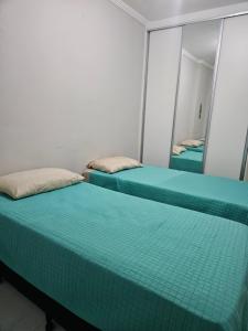 two beds in a room with a mirror at Apto Novo no Canto do Forte PG in Praia Grande