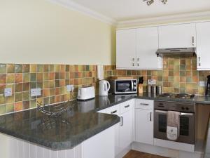 a kitchen with white cabinets and a black counter top at Dicks View in Ventnor
