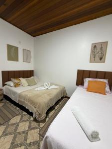 two beds in a room with white walls at Riso Suítes - Jantar Romântico in Santo Antônio do Pinhal