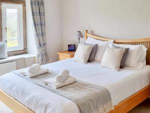 a bedroom with a white bed with towels on it at Barn End in Watermillock +21 photos