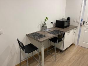 a kitchen with a desk with two chairs and a microwave at Vitospa in Cauffry