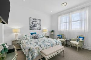 a bedroom with a bed and two chairs and a window at Waves at Warilla in Barrack Point