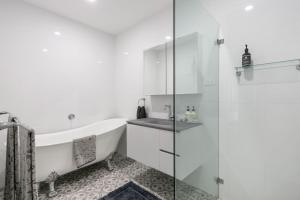 a white bathroom with a tub and a shower at Waves at Warilla in Barrack Point +17 photos