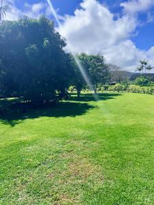 a sprinkler in a field with trees in the background at Coral Wave Cottage in Waialua +25 photos