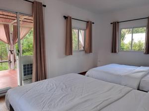 two beds in a room with two windows at ไร่เติมรัก - บ้านภูตระการ in Ban Khlong Kum