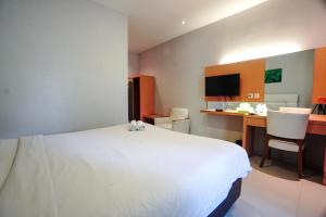 a bedroom with a large white bed and a desk at Buring Residence By TOS Malang in Samaan