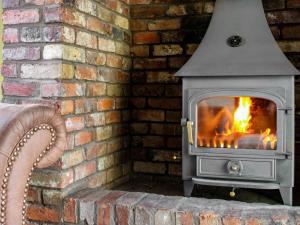 a fireplace in a brick wall with a stove at Green Lane Cottage in Newtown