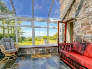 a living room with a red couch and a chair at Green Lane Cottage in Newtown
