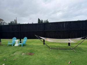 two chairs and a hammock in a yard with a fence at Hibiscus Hale - Perfect for 2! in Waialua