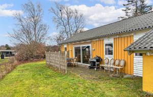 a yellow house with a grill and chairs in the yard at Amazing Home In Ørsted With Sauna in Ørsted +13 photos