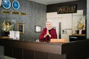 a woman standing behind a counter in a restaurant at Tripletree Majestiq Hotel in Pekanbaru