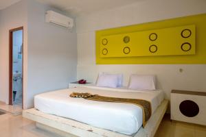 a bedroom with a white bed with a yellow painting on the wall at Tripletree Majestiq Hotel in Pekanbaru +50 photos