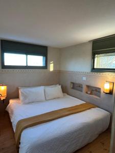 a bedroom with a large white bed with two windows at מים במדבר in Zuqim +3 photos