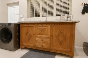 a kitchen with a wooden cabinet next to a washing machine at 12a Infinity Guesthouse in Pietermaritzburg +5 photos