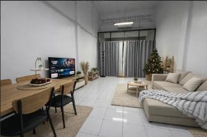 a living room with a table and a couch and a christmas tree at Cozy house hatyai in Sathani Khlong Rian