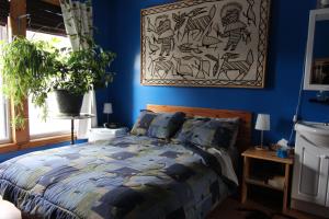 niebieska sypialnia z łóżkiem i zdjęciem na ścianie w obiekcie Gite L'Imprévu w Montrealu