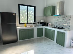 a kitchen with green cabinets and a black refrigerator at Cozy Palm Hills in Ban Nong Thale