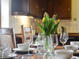 a table with wine glasses and a vase of flowers at Green Lane Cottage in Newtown