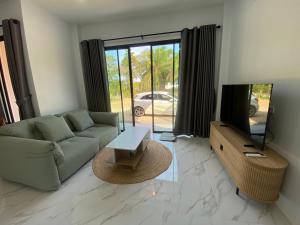 a living room with a couch and a tv at Cozy Palm Hills in Ban Nong Thale