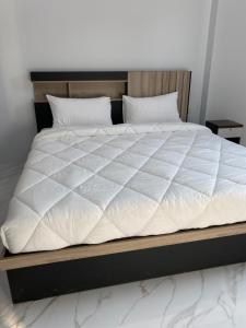 a large bed with a white comforter on it at Cozy Palm Hills in Ban Nong Thale