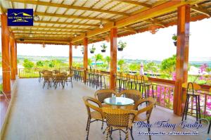 a restaurant with tables and chairs on a balcony at Bàu Trắng Garden in Ấp Nhơn Hòa