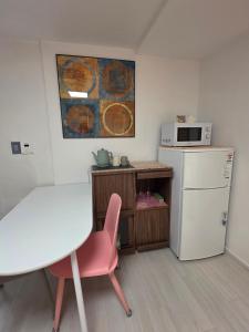 a kitchen with a white refrigerator and a pink chair at dalcom kunkuk in Seoul