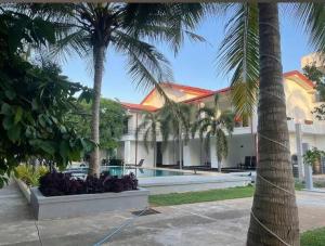 a building with a swimming pool and palm trees at Bellamoon Resort in Trincomalee