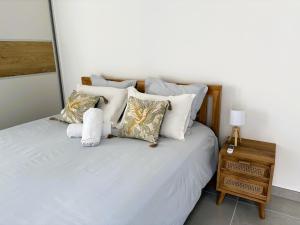 a bedroom with a bed with white sheets and pillows at SUNSET L'argonaute T3 70 m2 jardin et terrasse vue lagon in La Saline les Bains +38 photos