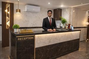 a man in a suit standing at a reception counter at Shahenshah Hotel in Civil Lines, Prayagraj in Prayagraj