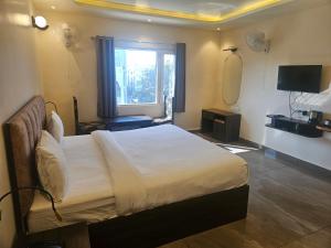 a bedroom with a bed with a mirror and a window at Shahenshah Hotel in Civil Lines, Prayagraj in Prayagraj