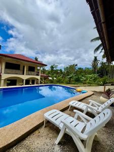 a pool with two lounge chairs next to a house at Villa Nicolasa in Siquijor