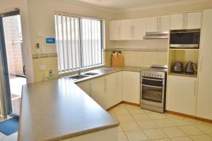 a kitchen with white cabinets and a stainless steel counter top at Blue Ocean Villa 7 - Kalbarri, WA in Kalbarri
