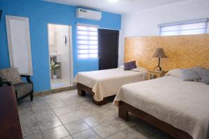a bedroom with two beds and a chair and a mirror at Suite moderna para 2, a 5 min del Centro in Ciudad Victoria