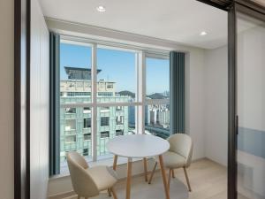 a dining room with a table and chairs and a large window at 센텀 뉴시즈 호텔 in Millak-tong