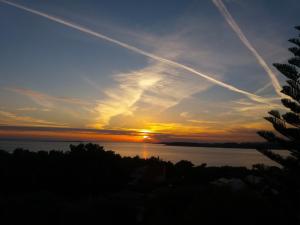 a sunset over the water with contrails in the sky at Niko Studios in Lassi
