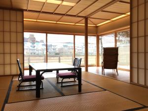 a dining room with a table and chairs and windows at Maru Izumiyacho in Kyoto