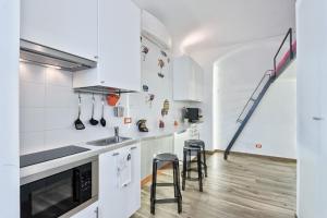a kitchen with white cabinets and a sink and stools at LittleAndCosy in Turin