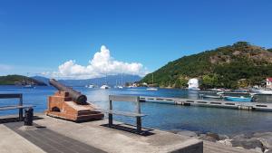 a dock with a bench and boats in the water at Location Marigot in Terre-de-Haut