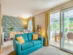a living room with a blue couch and a dining room at Cherry Tree Corner in Ashbourne
