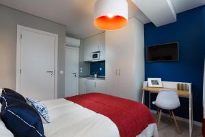 a bedroom with a bed with a red blanket and a desk at Chic Studios in Parede