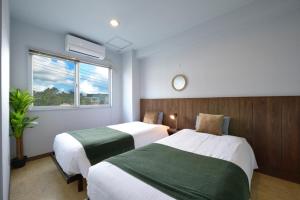a bedroom with two beds and a window at Sea Side TOYA in Yomitan